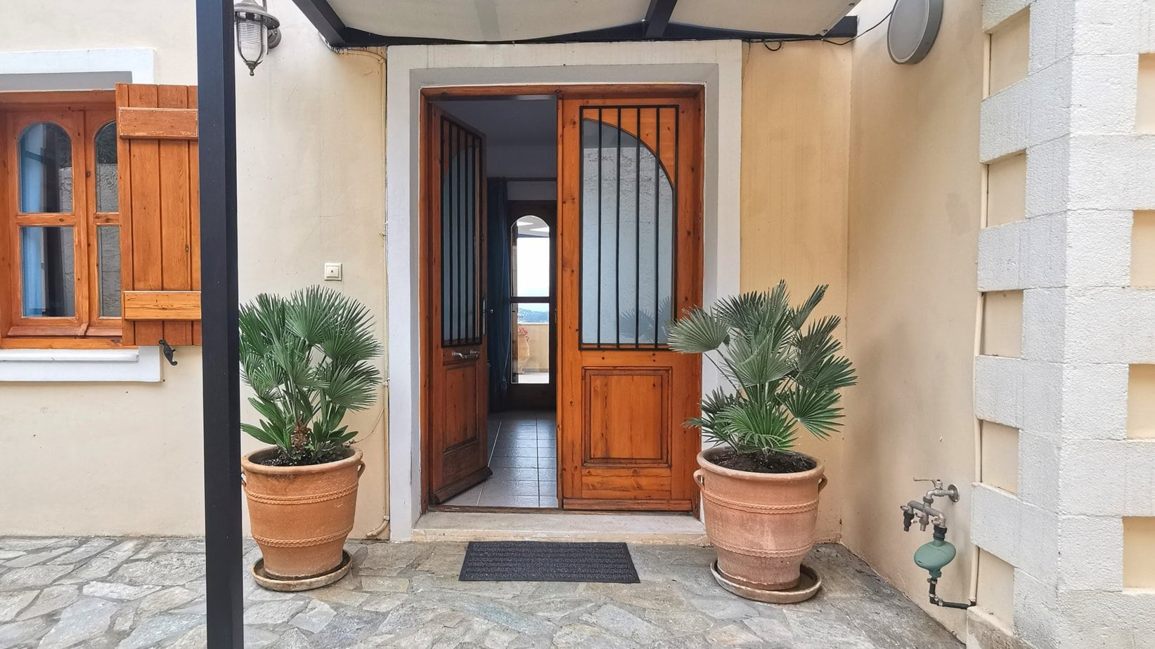 The front door at Villa Koumos. Plants in pots either side. The door is open.