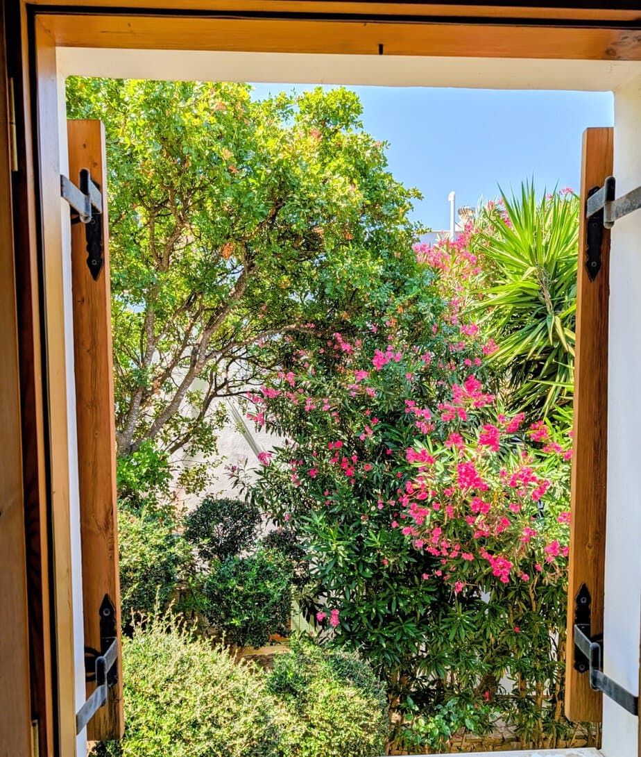 Flowering Mediterranean garden seen through an open window at Villa Koumos